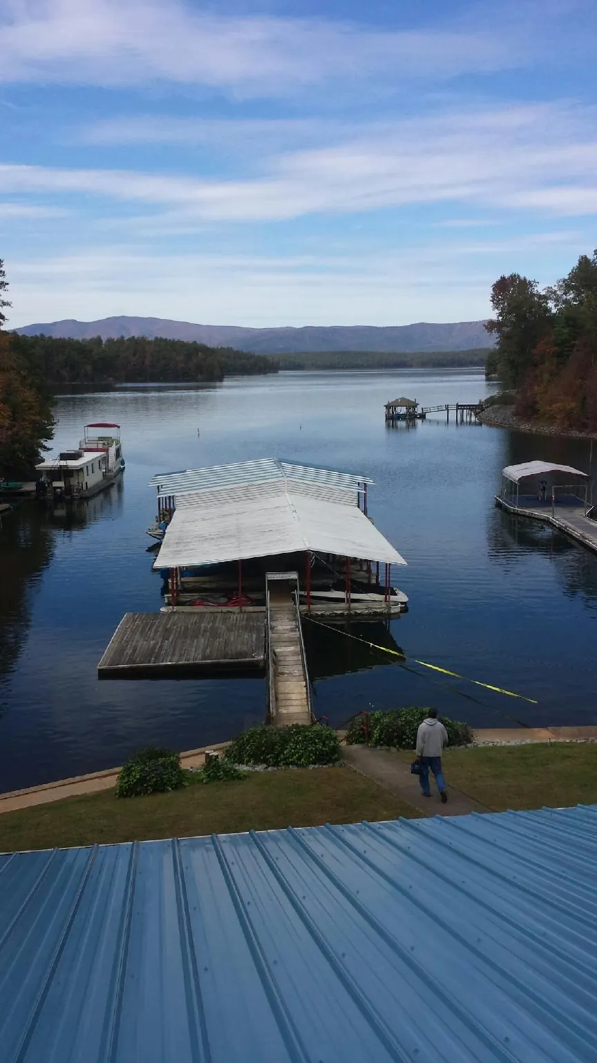 View across a lake from a newly installed blue metal roof in Monroeville
